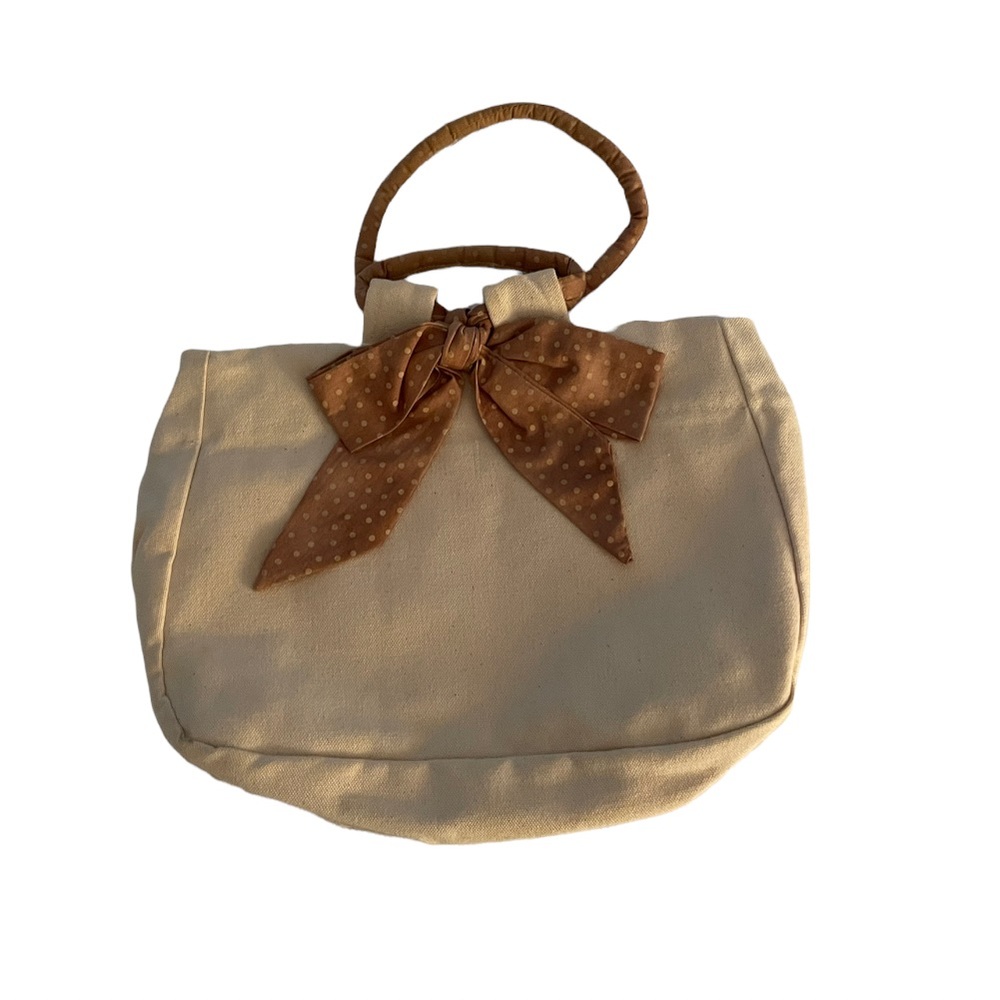 Small canvas bag/purse with accent bow on front.
